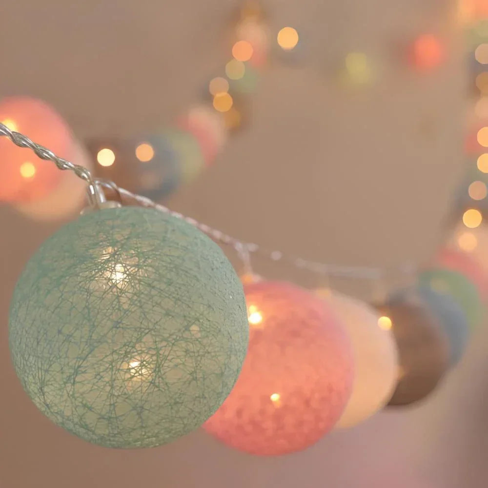 Warm LED garland of cotton balls artfully arranged on a shelf for aesthetic room lighting.