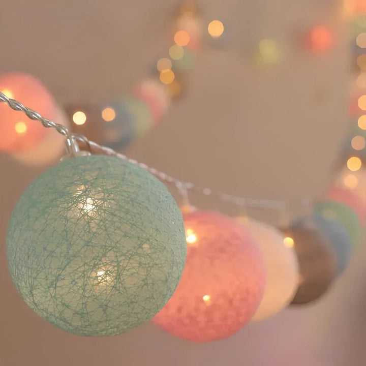 Warm LED garland of cotton balls artfully arranged on a shelf for aesthetic room lighting.