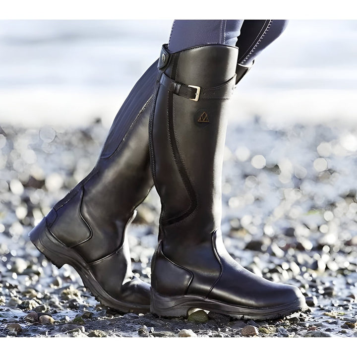 Elegant women's knee-high riding boots with a stylish buckle strap, ideal for equestrian looks.