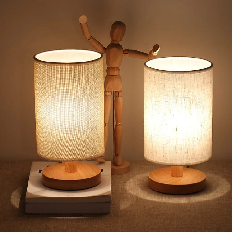 Dimmable Organic Glow Table Lamp with light wood base and fabric shade for cozy bedroom mood lighting.