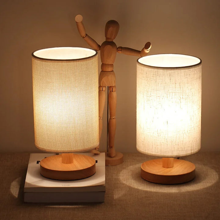 Dimmable Organic Glow Table Lamp with light wood base and fabric shade for cozy bedroom mood lighting.
