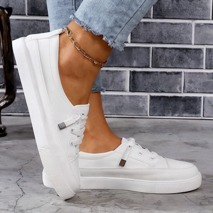White women's low profile flat sneakers with classic lace-up design, perfect for everyday casual wear.