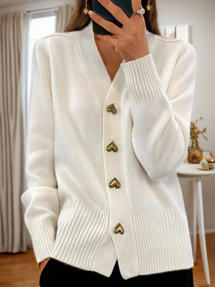Detail of a woman fastening the buttons on a chic V-neck long sleeve cardigan, perfect for fall fashion.