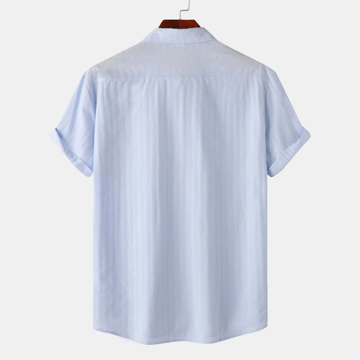 Close-up of the collared men's short sleeve button-down shirt, showing chest pocket detail. Smart casual style.