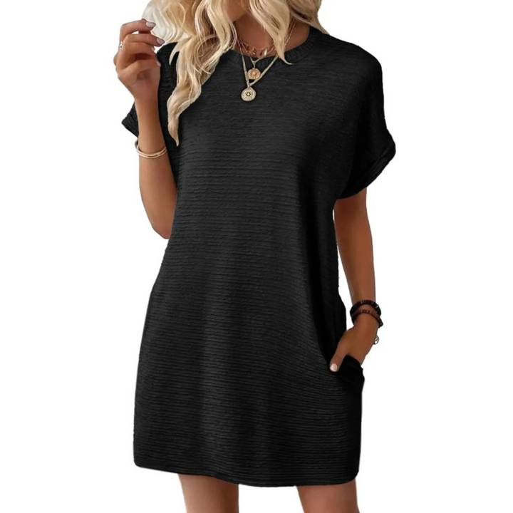 Side view of woman in an oversized t-shirt mini dress, highlighting short sleeves, comfortable fit & convenient side pockets.