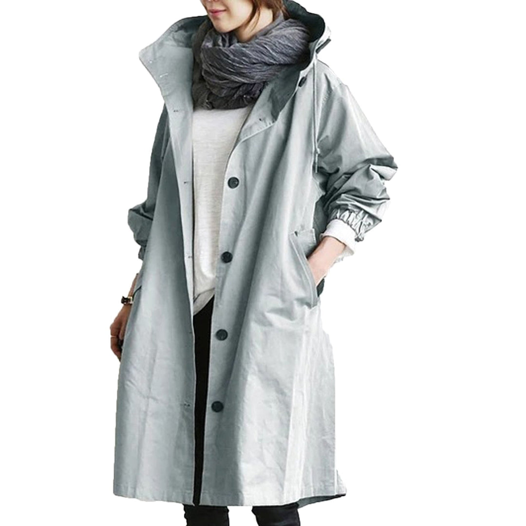 Woman walking in a city street wearing a sophisticated long waterproof raincoat, staying dry with elegant flair.