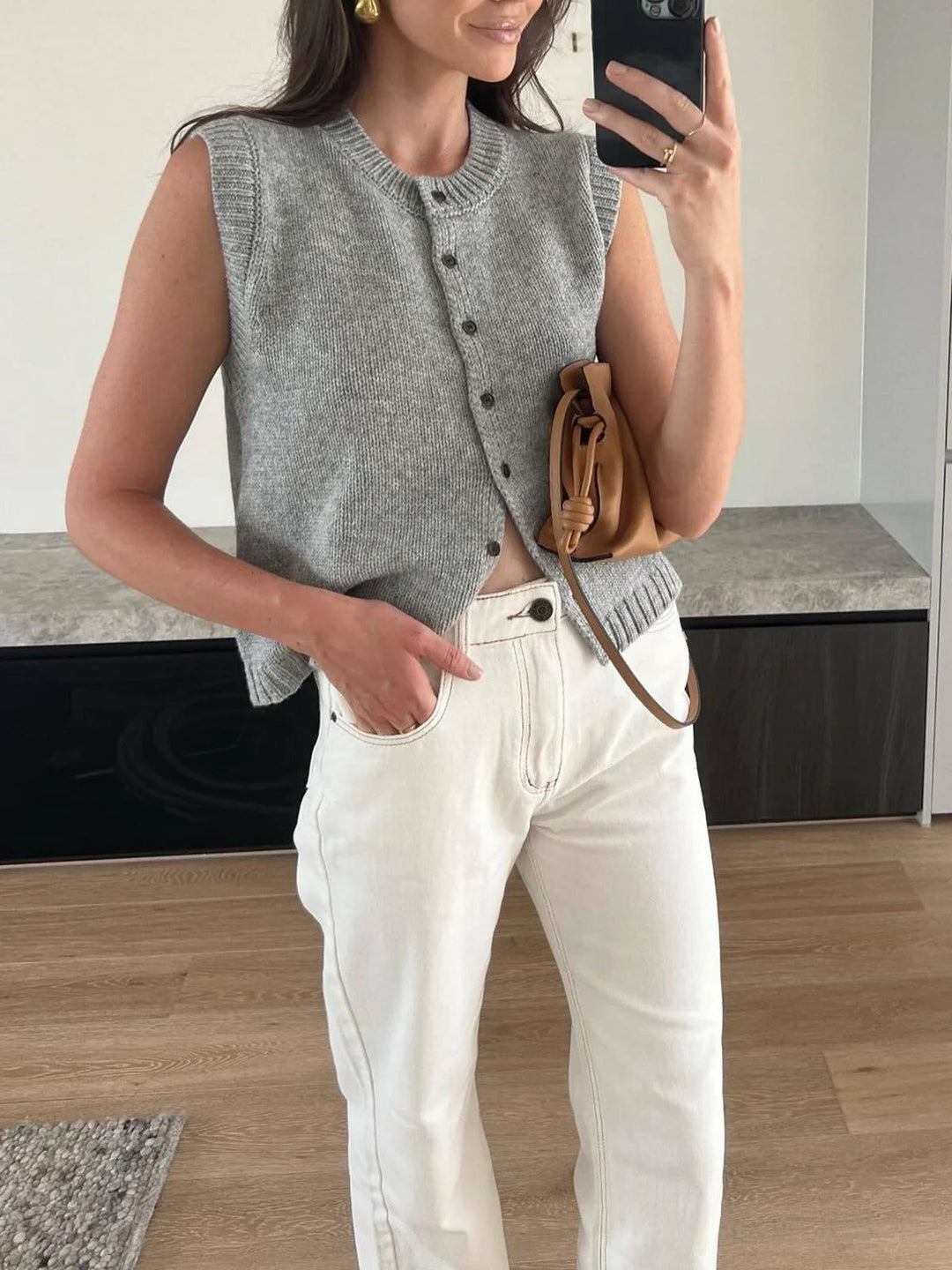 Light grey women's button-up sweater vest, a chic layering piece for modern style & transitional outfits.
