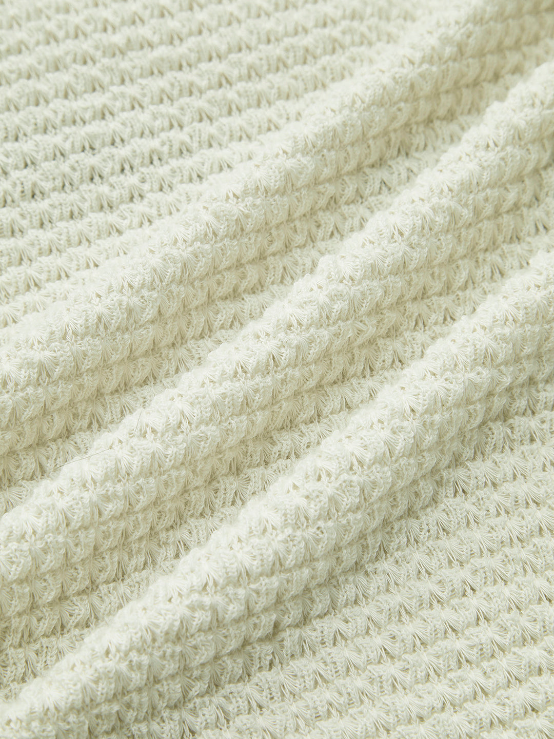 Close-up of women's textured waffle knit long sleeve top, showcasing cozy fabric for winter comfort.