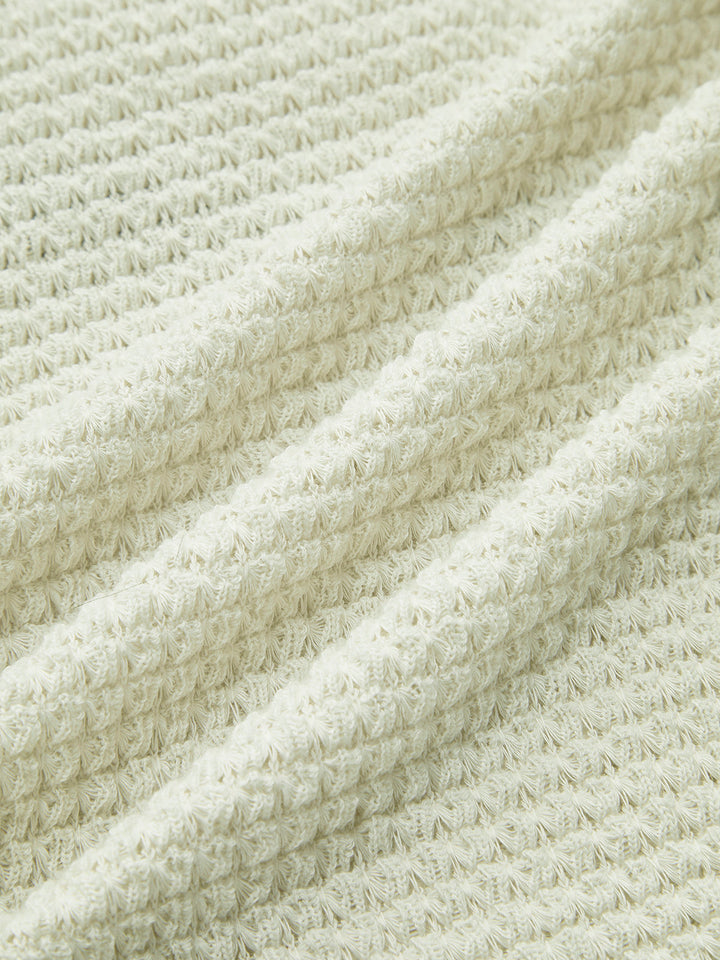 Close-up of women's textured waffle knit long sleeve top, showcasing cozy fabric for winter comfort.