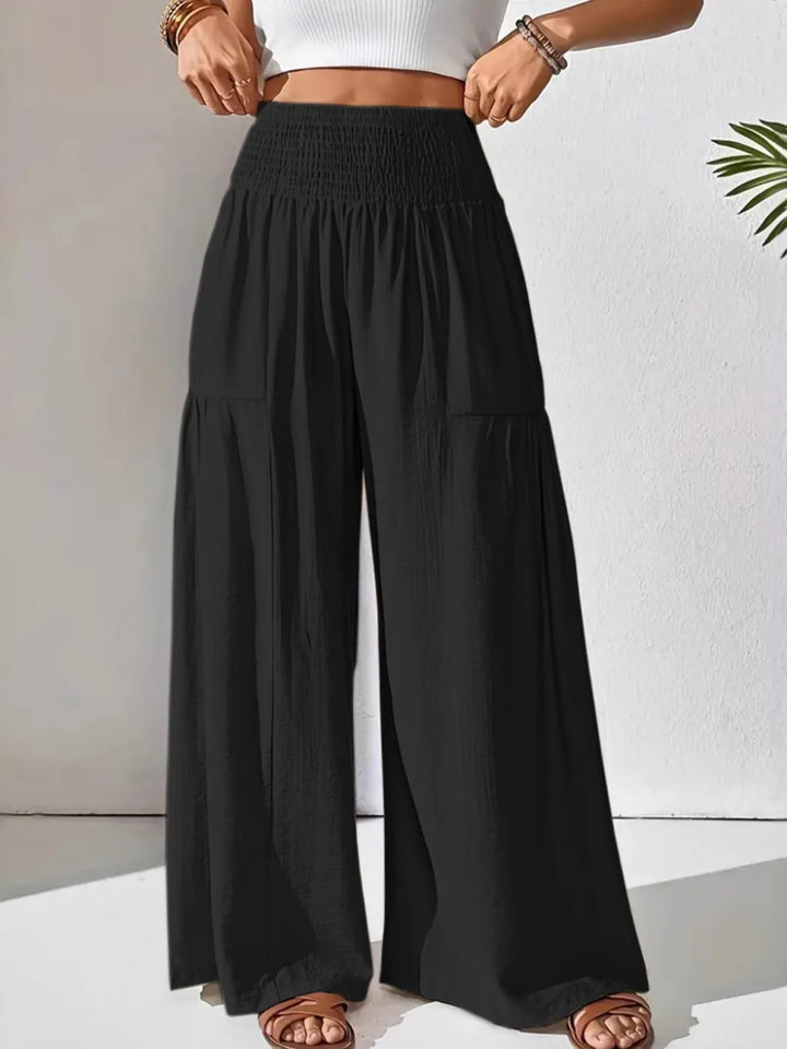 Close-up of smocked waist & wide leg on women's flowy pants, highlighting comfortable, loose fit design.