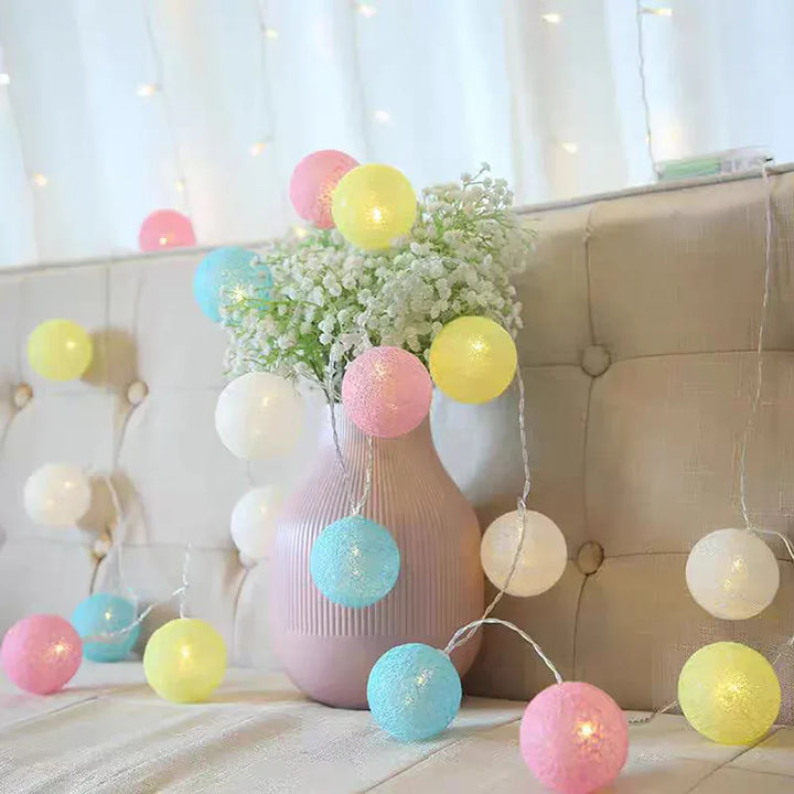 Cotton ball LED string lights draped over a headboard, providing warm bedroom ambiance.