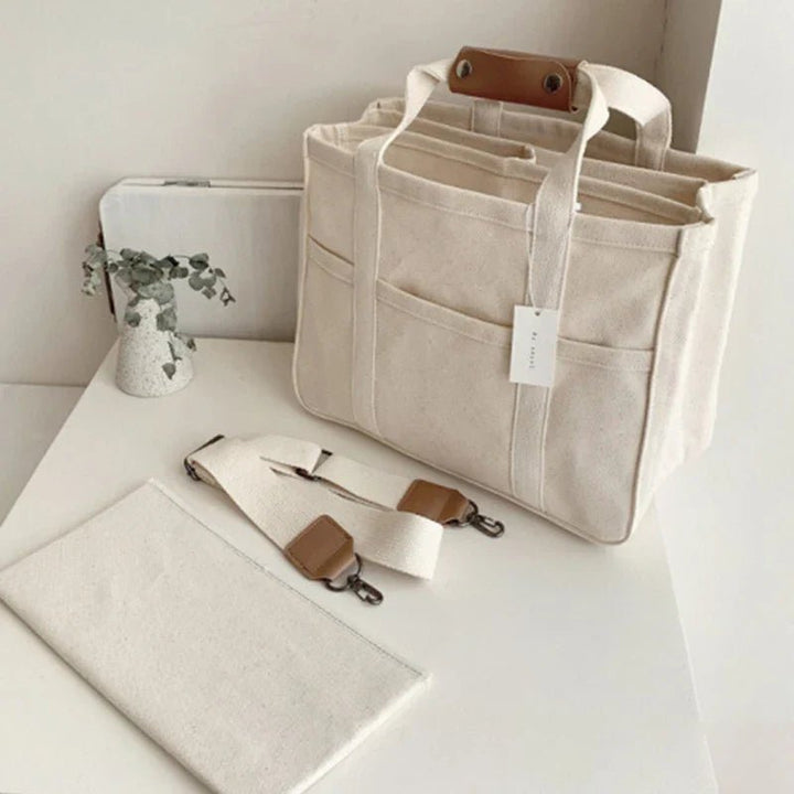Versatile black canvas tote bag for women, can be worn as a shoulder bag or crossbody, with many pockets.
