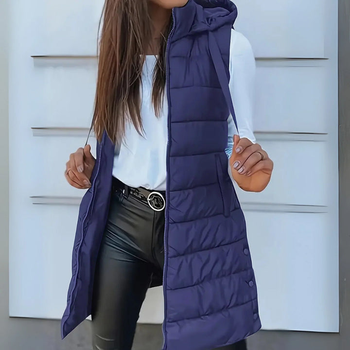 Modern women's lightweight hooded long puffer vest, providing warmth without bulk.
