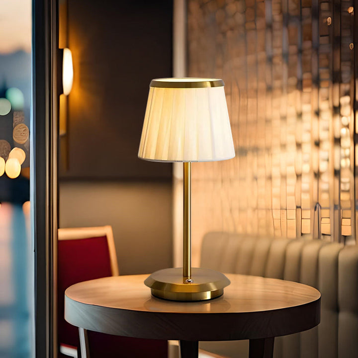 Dimmable table lamp with fabric shade & elegant brass base. Rechargeable LED offers versatile cordless modern lighting.