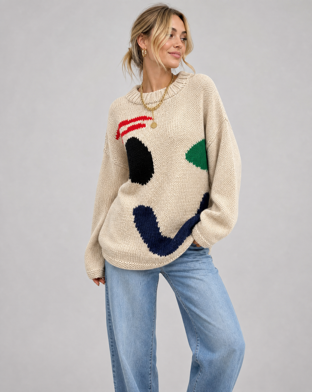 Women's oversized knit sweater with a bold smiley face, perfect for cozy and stylish casual wear.