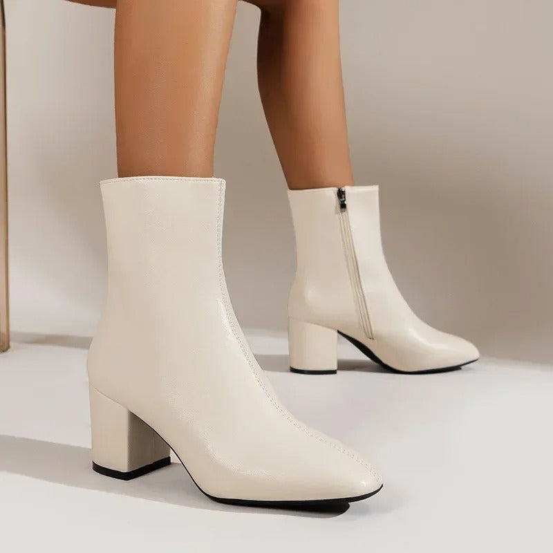 Close-up of elegant women's pointed toe ankle boots, highlighting the sleek design and sturdy block heel.