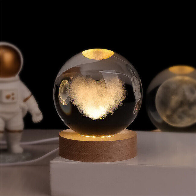 Crystal ball lamp featuring a stunning 3D engraved galaxy design, illuminated from its sturdy wooden base.