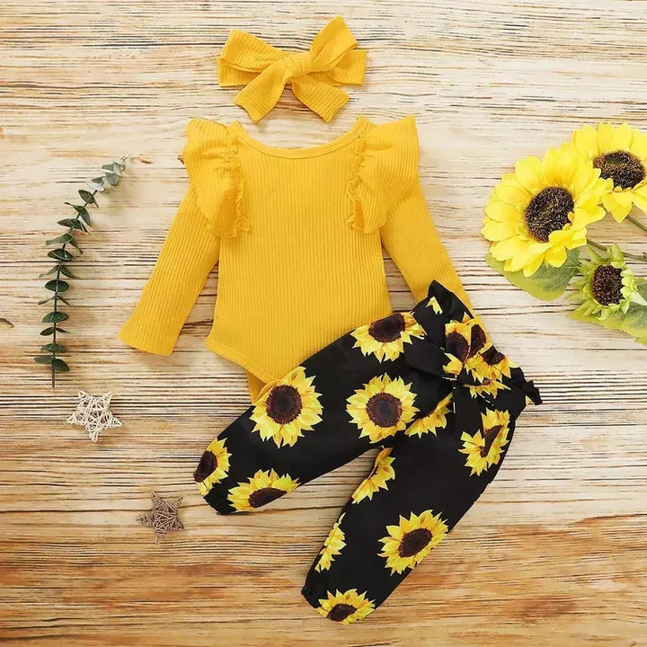Close-up of vibrant sunflower print on soft fabric of baby girl's 2-piece fall outfit.
