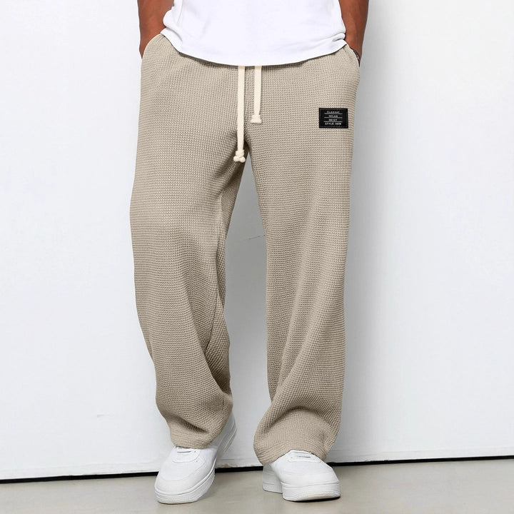 Man wearing stylish wide leg waffle knit drawstring trousers, perfect for relaxed casual wear.