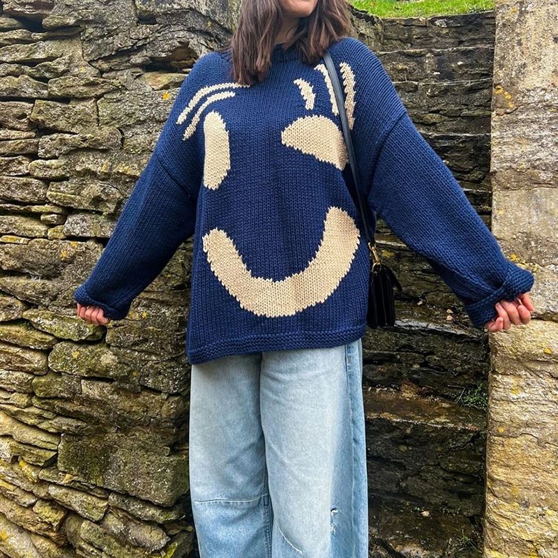 Soft, loose fit women's knit sweater with an oversized smiley face design, perfect for comfy everyday wear.