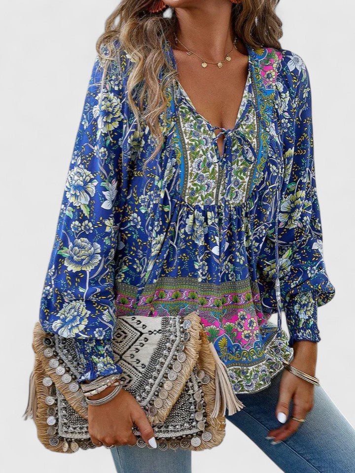 Woman wearing a vibrant paisley print flowy long sleeve boho blouse. Ideal for summer casual style.
