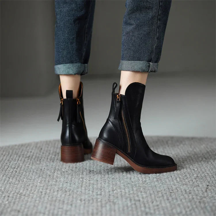 Close-up of elegant women's black zip ankle boots, highlighting the stylish zipper and premium material.