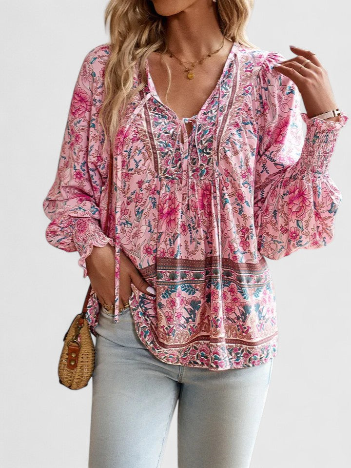 Close-up of women's lace-up V-neck blouse, featuring smocked cuffs & vibrant paisley print. Boho casual top.