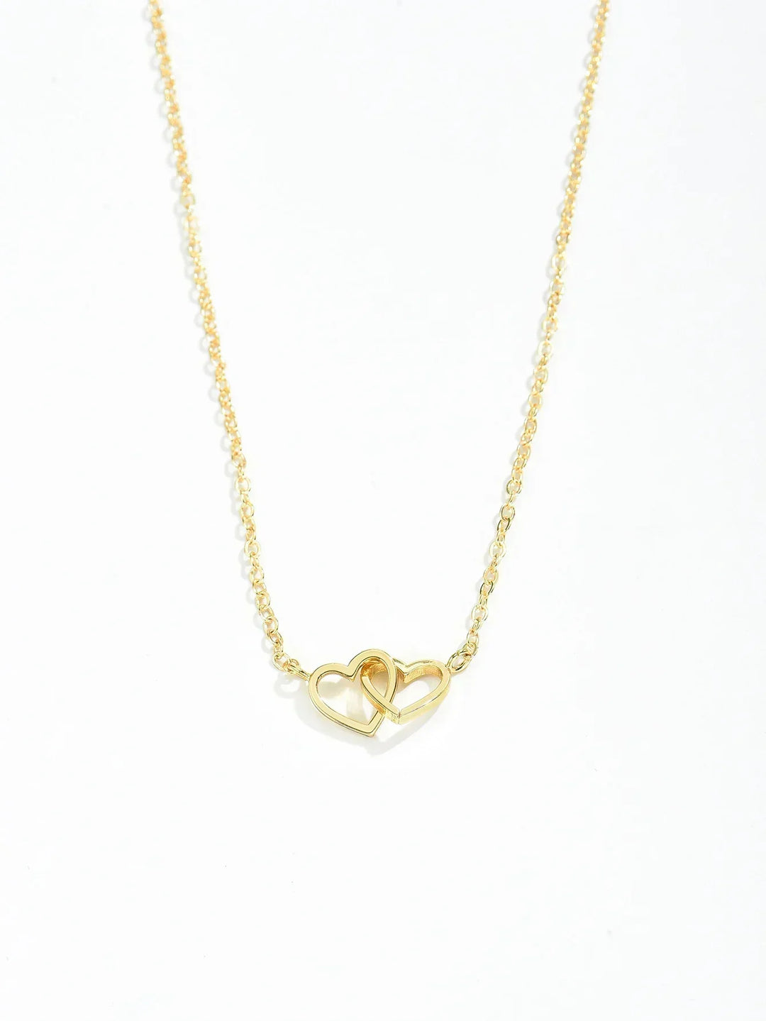 Close-up of delicate gold vermeil interlocking heart pendant, women's necklace on sterling silver chain.