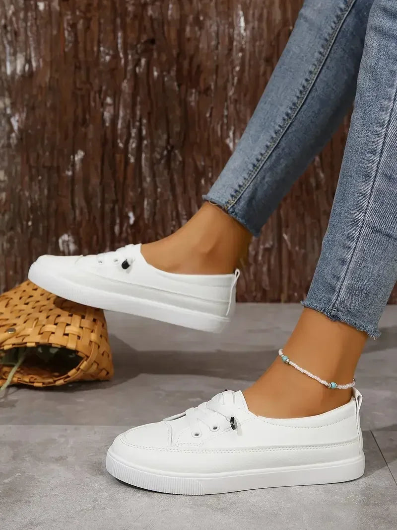 Stylish white flat women's sneakers featuring a classic lace-up design and a comfortable round toe.