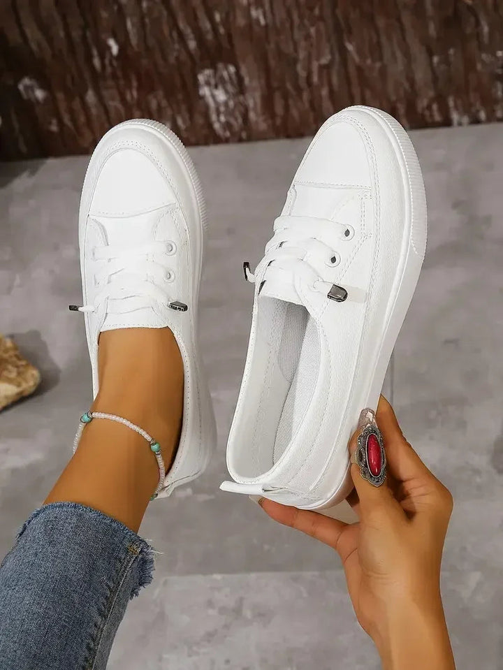 Versatile white lace-up flat sneakers for women, ideal for spring and summer casual outfits.
