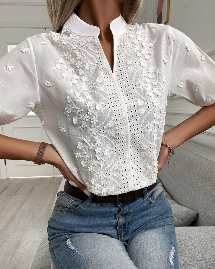 Chic women's V-neck blouse featuring intricate floral embroidery & comfortable puffed short sleeves. Versatile top.