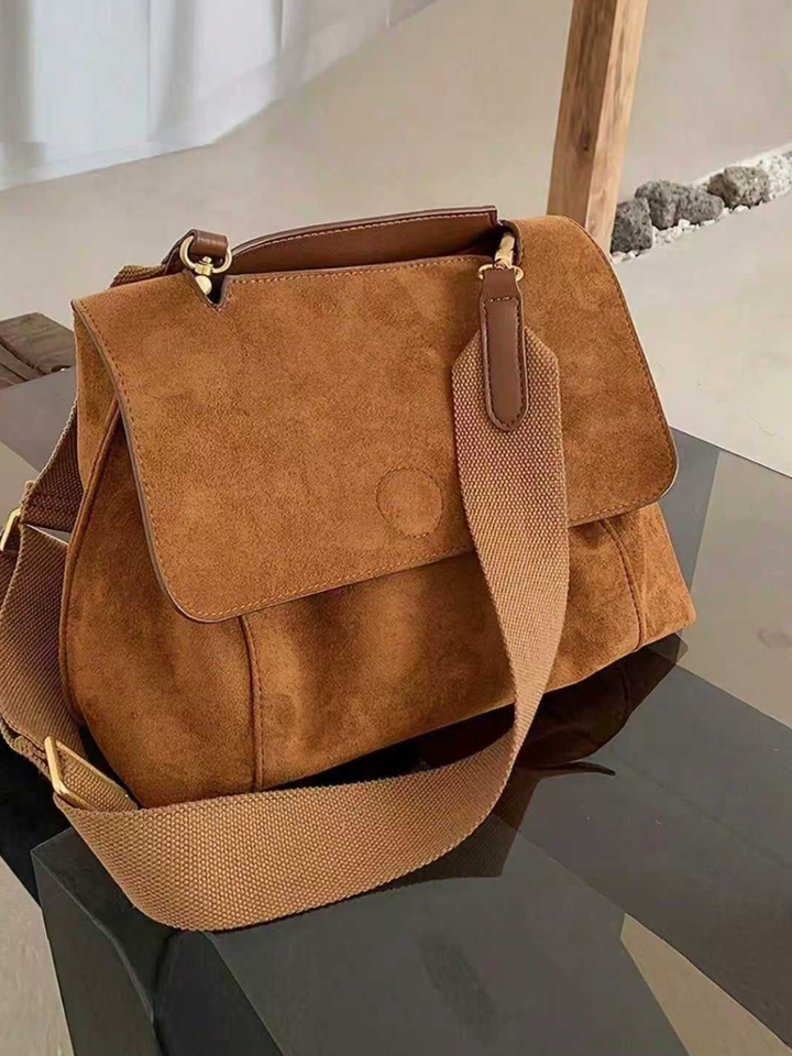 Front view of women's brown crossbody bag, highlighting adjustable strap & flap closure. Versatile shoulder bag.