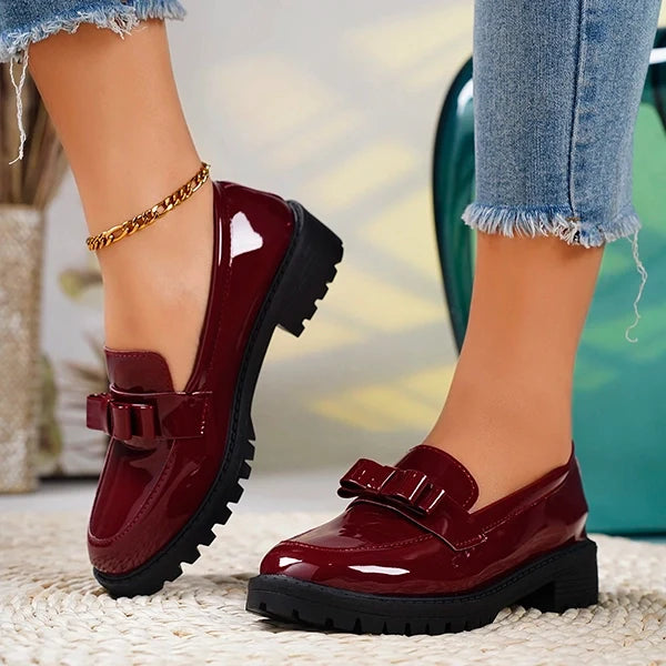 Women's slip-on platform loafers with a distinct bow & glossy finish, designed with a chunky sole for style.