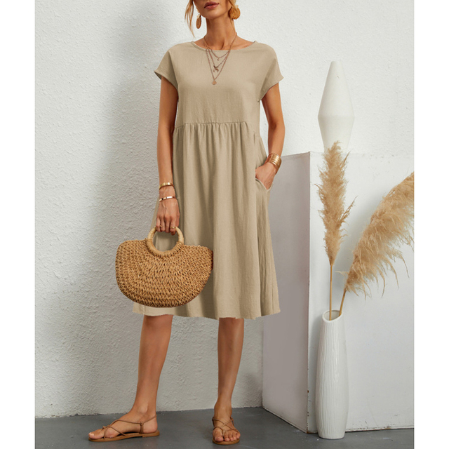 A woman wears a flowing blue summer midi dress with short sleeves & a round neck, perfect for casual everyday wear.