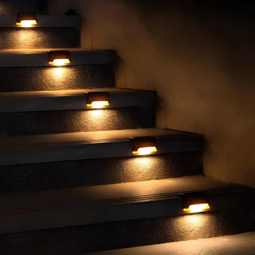 Outdoor solar step lights glowing warmly on a concrete pathway, demonstrating automatic dusk-to-dawn function.