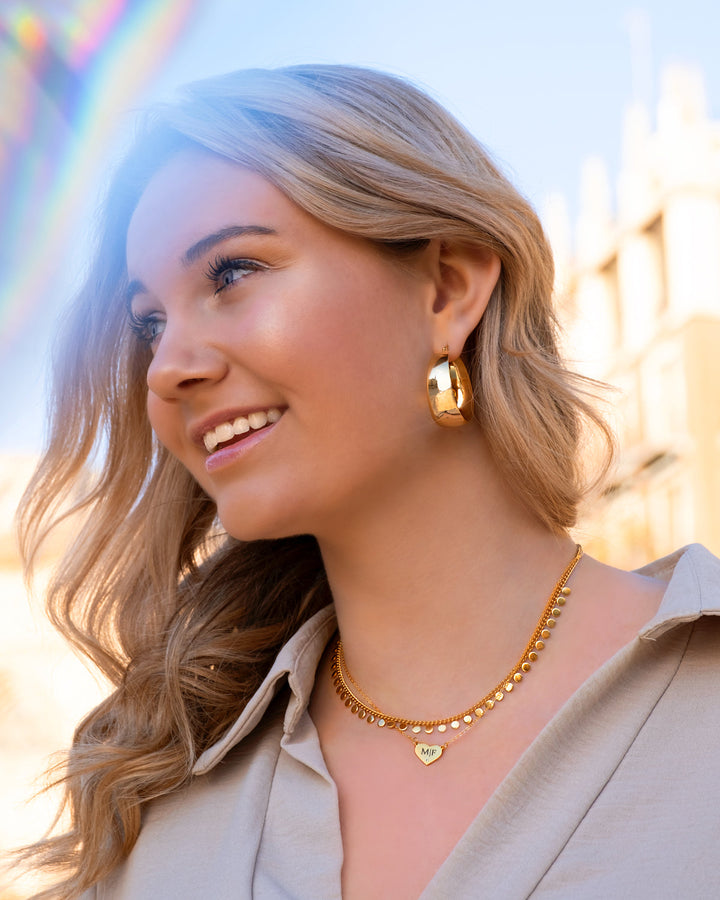 Close-up of women's bold gold-plated & sterling silver statement hoop earrings, elegant design.
