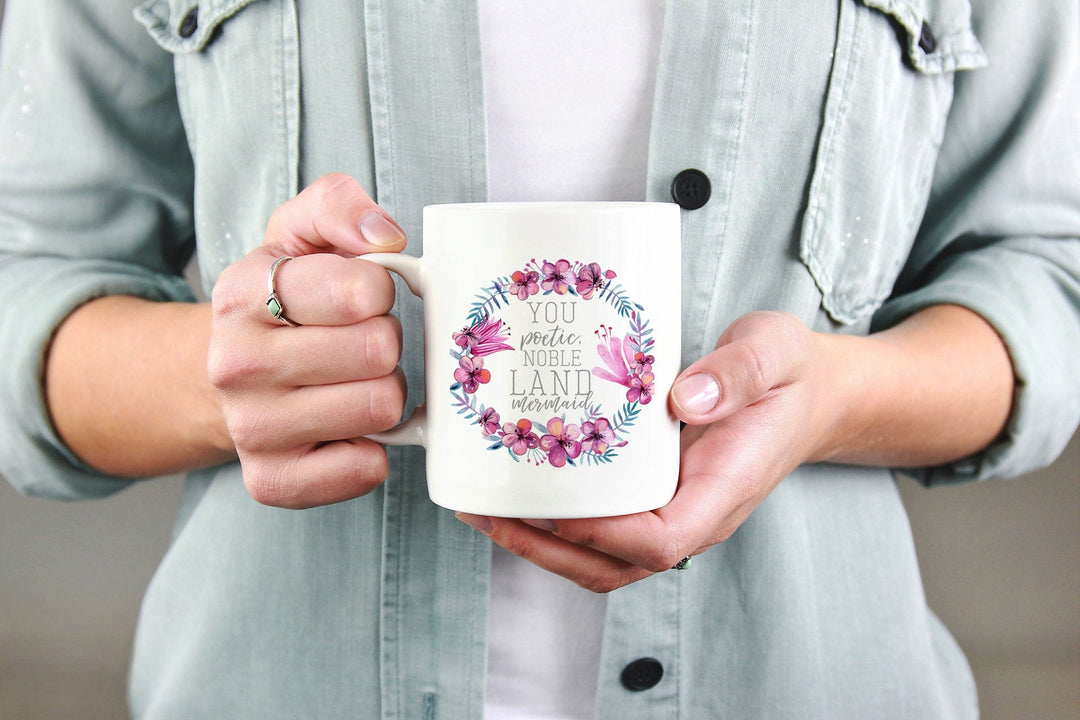 High-quality white ceramic coffee mug with beautiful floral wreath and a charming quote, suitable for hot drinks.