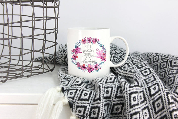 Elegant white ceramic coffee mug with delicate floral wreath design & uplifting quote, perfect tea cup.