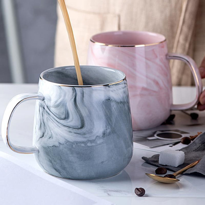 Elegant white ceramic coffee mug with a refined marble pattern and gold rim for luxurious drinkware.