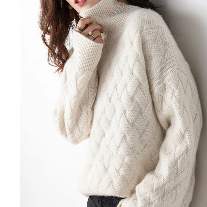 Close-up of women's chunky knit turtleneck jumper. Features a modern geometric design, cozy for cold weather.