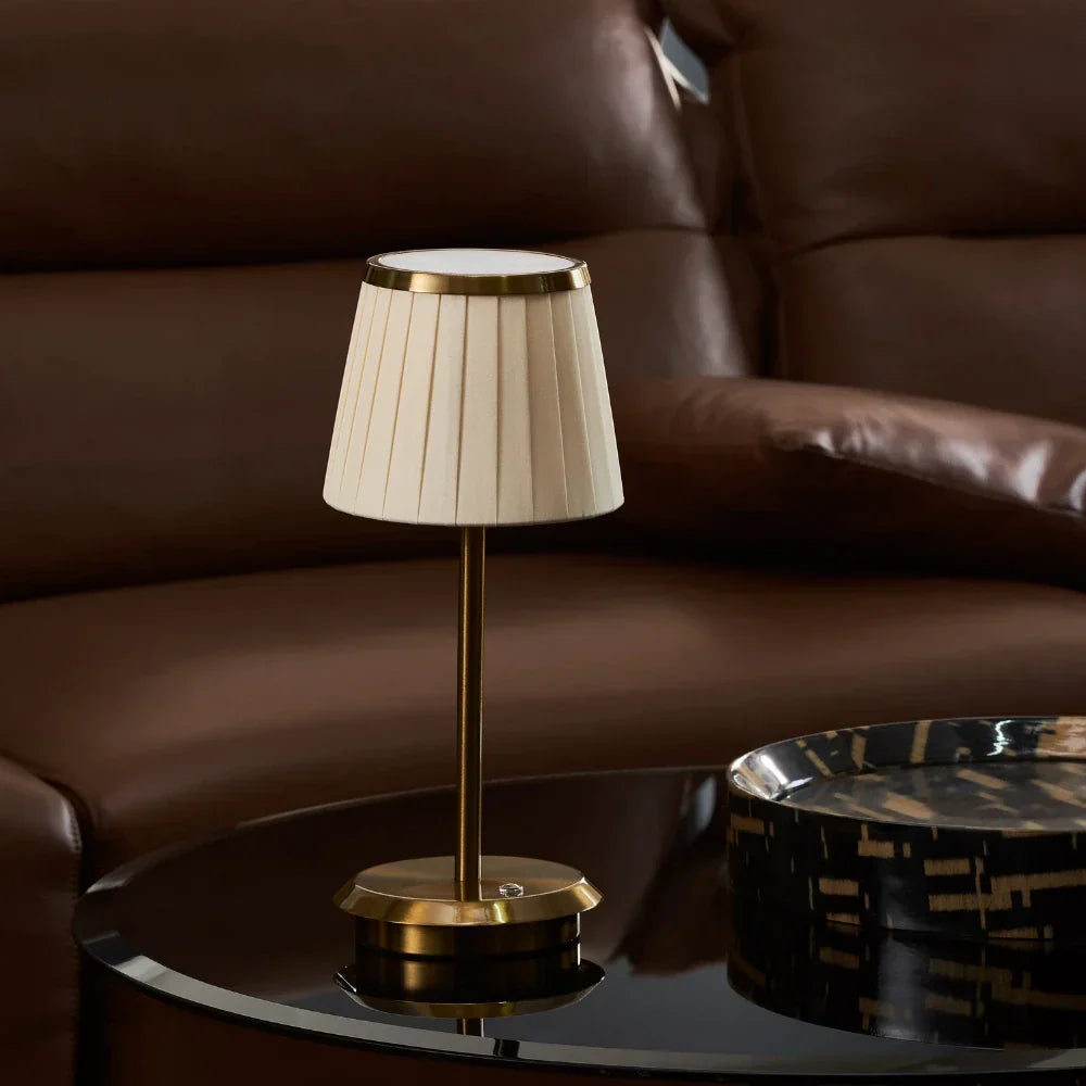 Contemporary gold table lamp with a fabric shade & dimmable LED. Rechargeable & portable, ideal for modern ambiance.