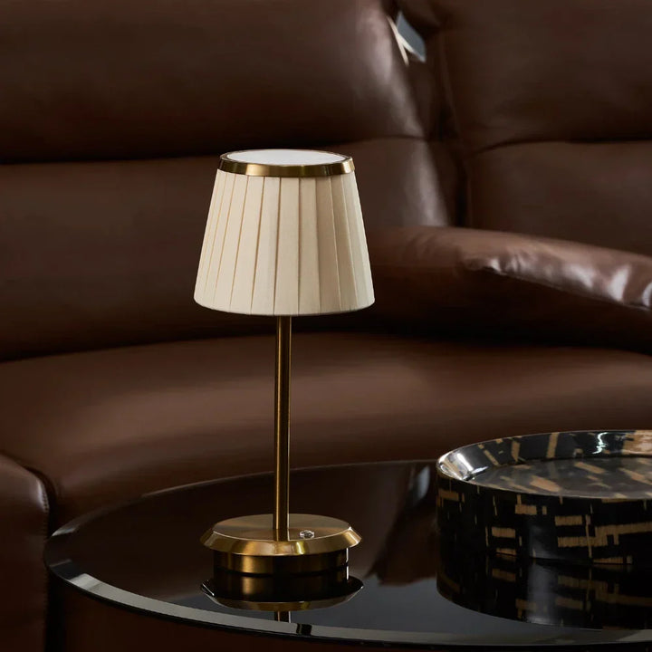 Contemporary gold table lamp with a fabric shade & dimmable LED. Rechargeable & portable, ideal for modern ambiance.
