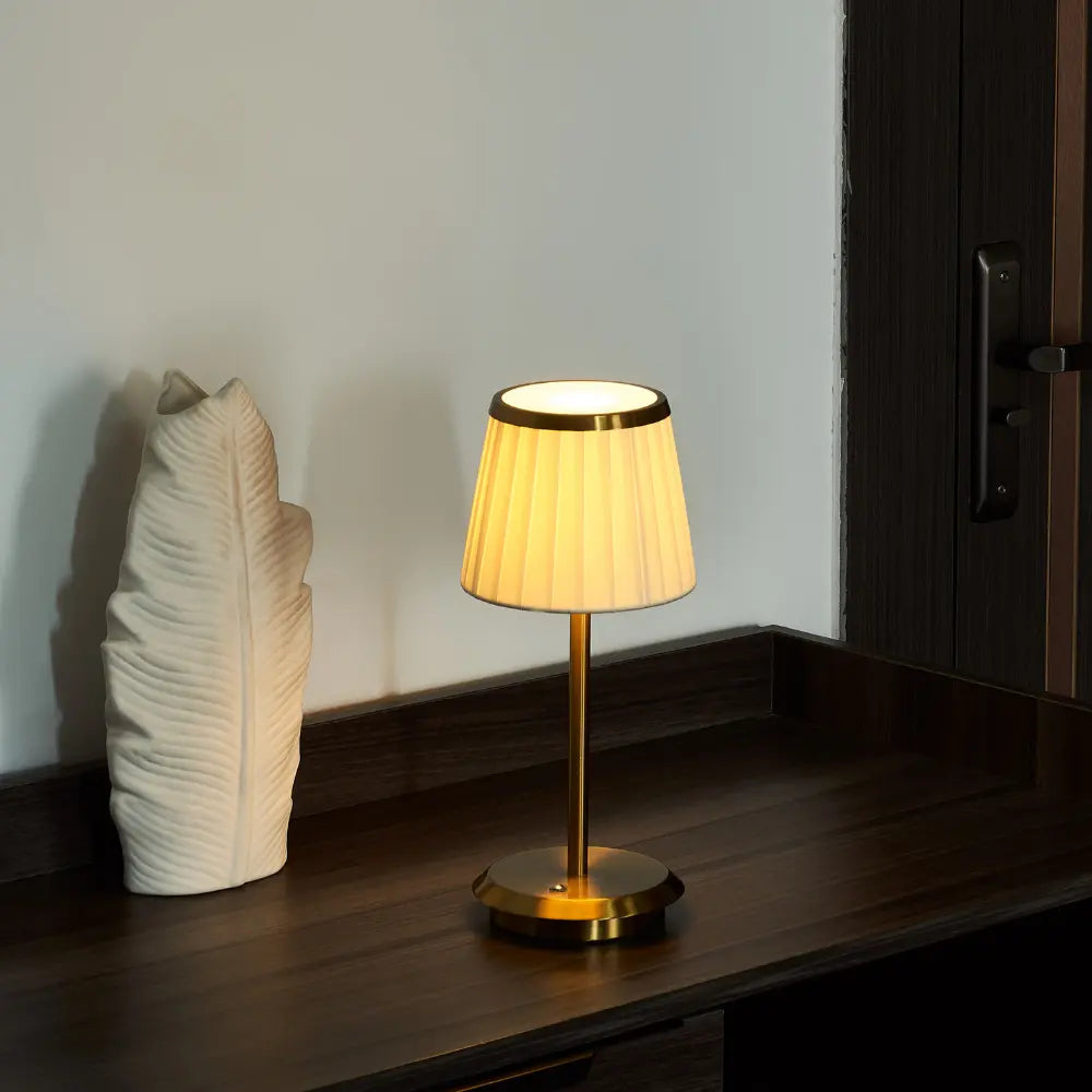 Sleek modern table lamp with brass base, dimmable LED, & waterproof design. Rechargeable & cordless for versatile use.