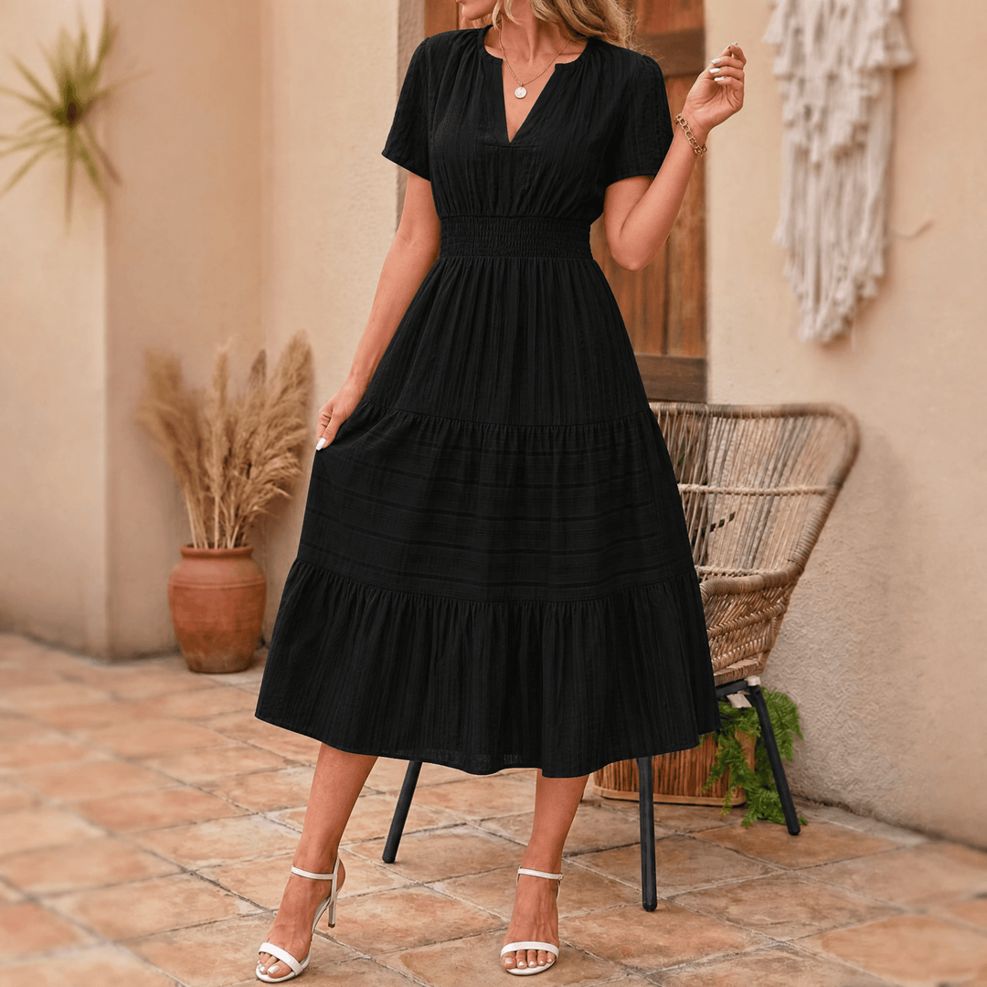 Smocked waist detail on a women's elegant tiered midi dress with V-neck, short sleeves, and side pockets.