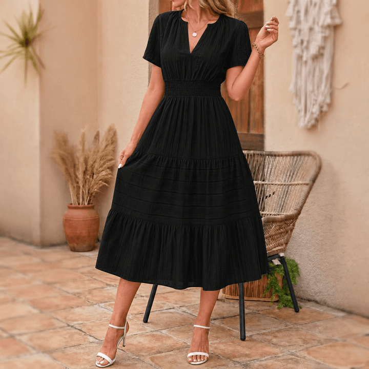 Smocked waist detail on a women's elegant tiered midi dress with V-neck, short sleeves, and side pockets.