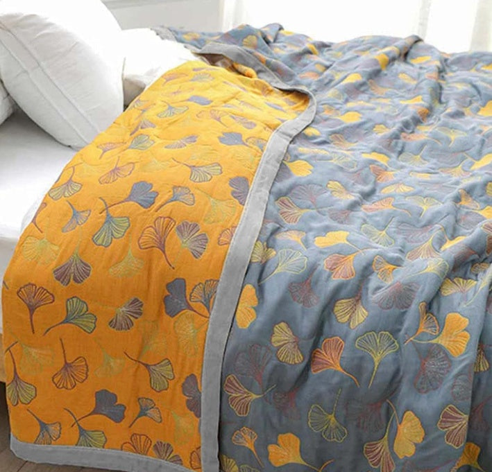 Cozy ginkgo leaf throw blanket in elegant yellow & blue. Reversible design adds stylish nature-inspired decor.