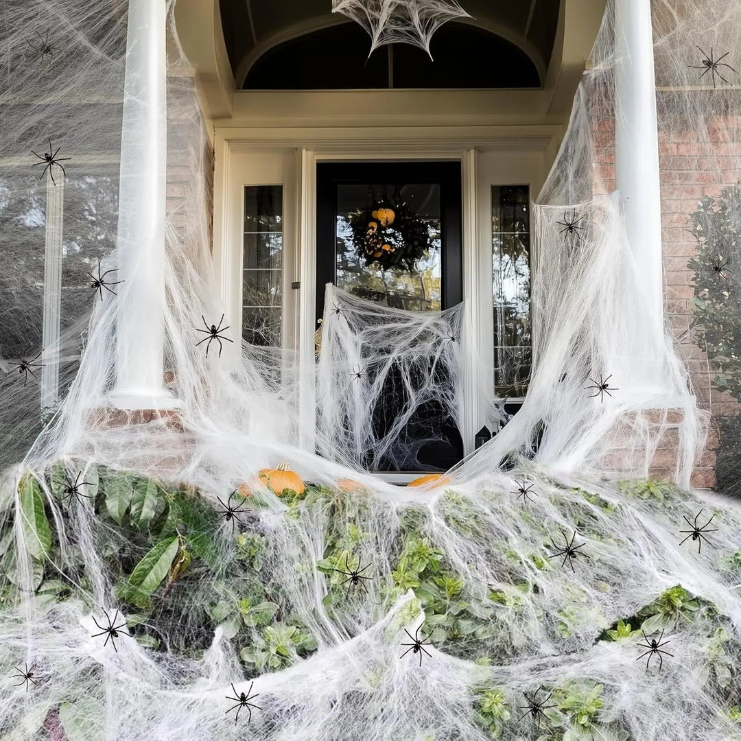 Spooky white stretch spider webs draped on garden bushes, ideal outdoor Halloween decoration for a haunted house.