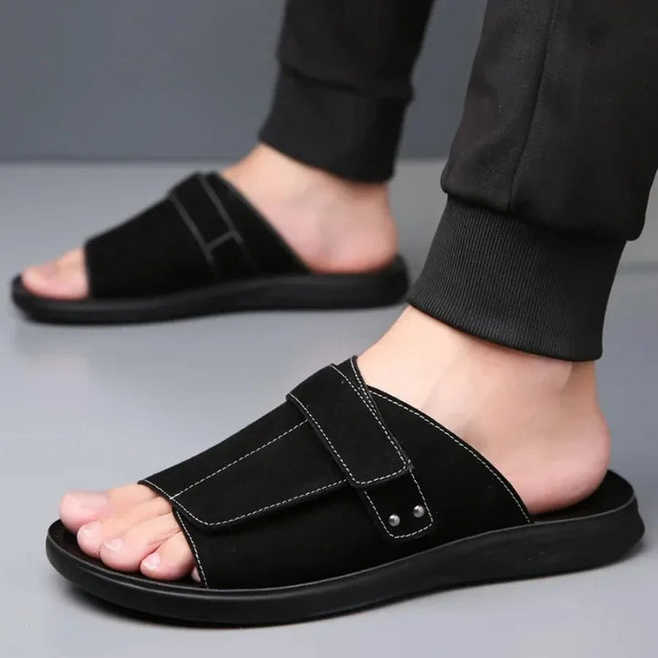 Pair of men's comfort slides, black with adjustable strap, suitable for beach, pool, or everyday slip-on wear.