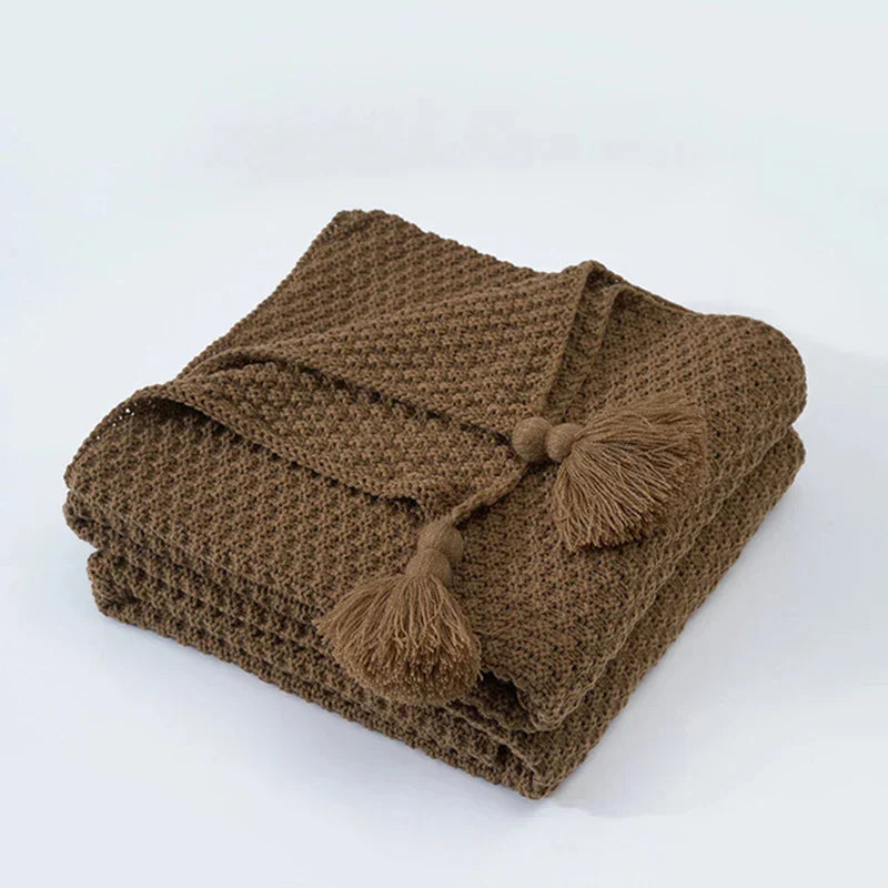 Luxurious knitted wool throw blanket with tassels, a cozy addition to any living space.