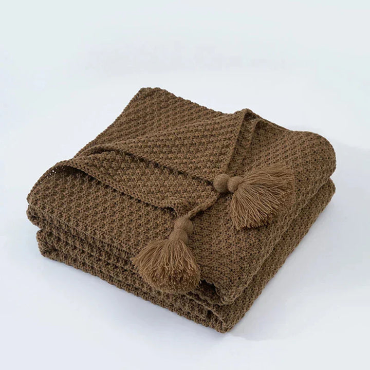 Luxurious knitted wool throw blanket with tassels, a cozy addition to any living space.